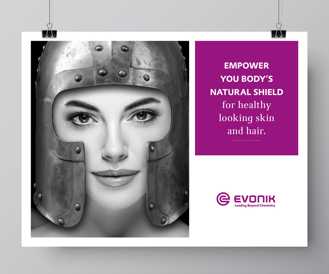 Ein Beautymodel, das seine Haut schützt, indem es einen Ritterhelm trägt; Headline: „Empower your body’s natural shield for healthy looking skin and hair.“